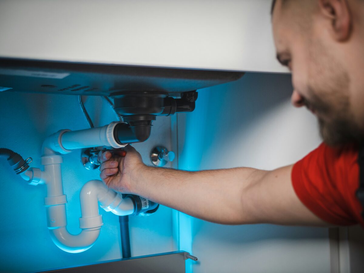 Plumber repairing under-sink pipes in a Bronx apartment